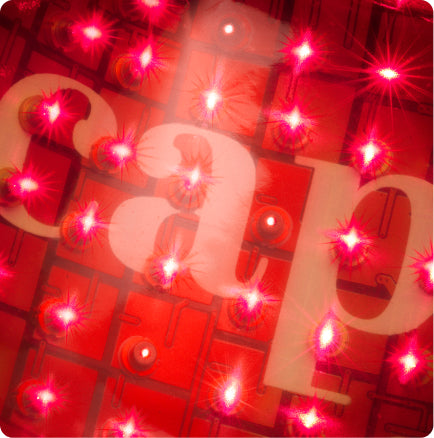 Close-up of illuminated red LED lights with the lowercase white letters “c,” “a,” and “p” partially visible in the background. The lights create a bright, glowing effect over the text.