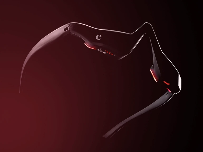 A sleek, black wearable headset with red accent lights is shown against a dark background. The device has a modern, futuristic design, curving around the eyes and temples.