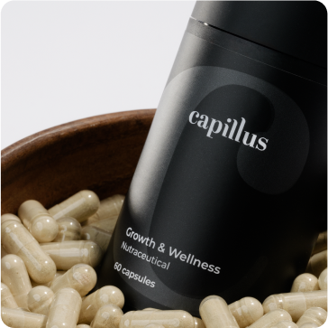 A black bottle labeled capillus Growth & Wellness Nutraceutical 60 capsules is displayed in a bowl filled with beige capsules.