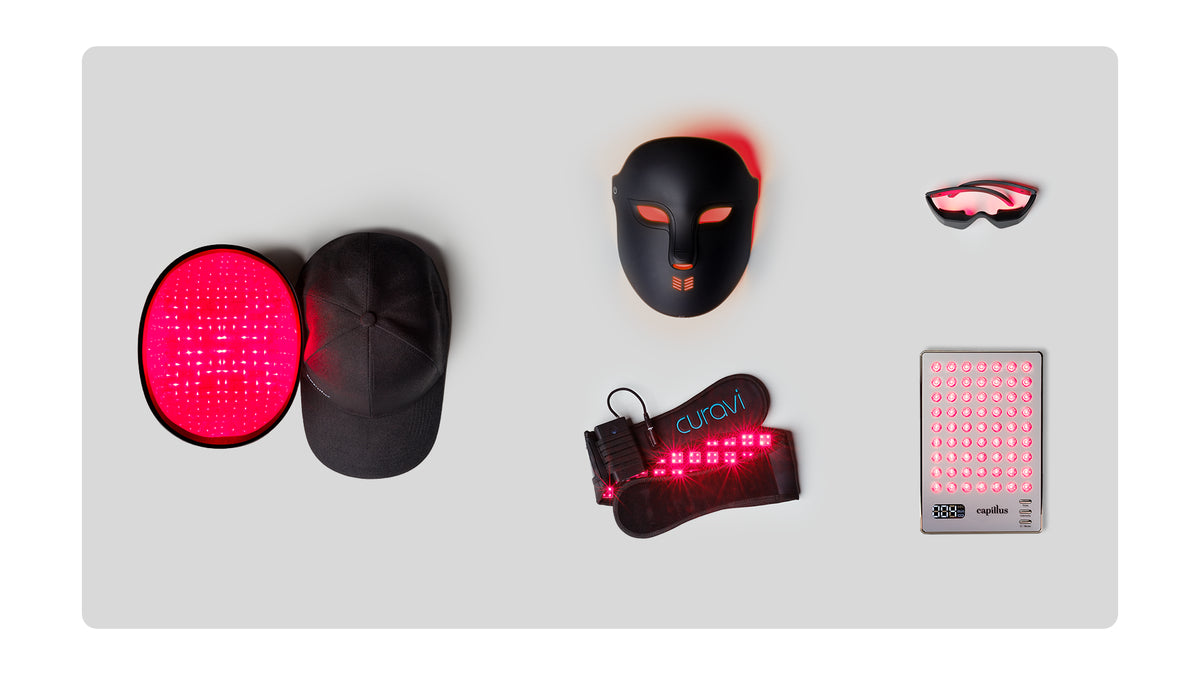 A variety of wearable red light therapy devices, including a mask, cap, eye goggles, foot wrap, and two flat light panels, arranged on a light gray background.