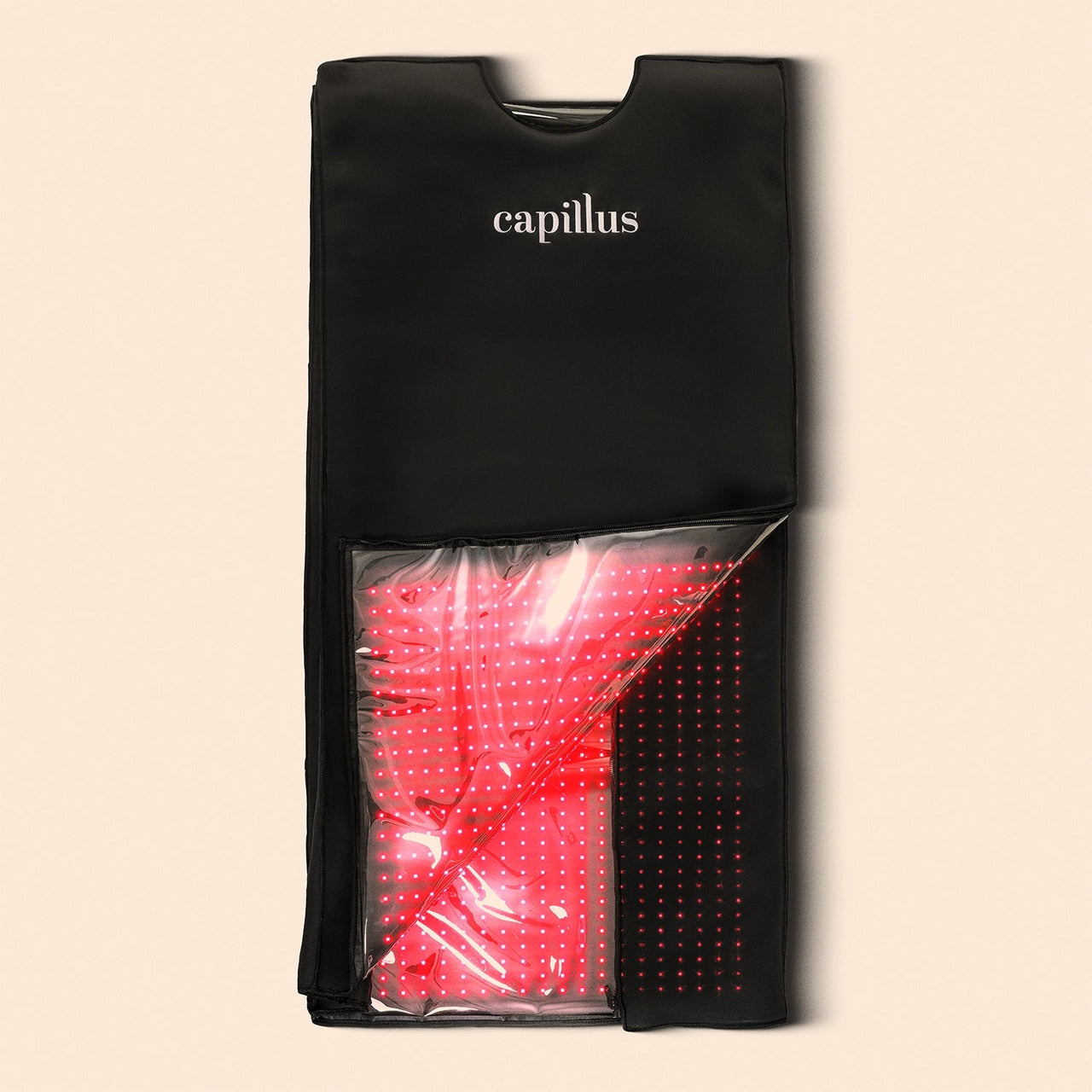 The Capillus Healing Pod, a black Capillus-branded pad with a clear section displaying red LED lights for red light therapy or hair treatment, is shown on a beige background.