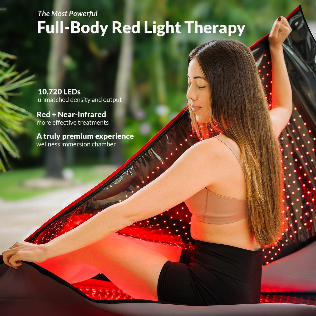 Une femme est assise à l'intérieur d'une capsule de soins Capillus rouge, ouverte et portable, dont l'intérieur est tapissé de nombreuses petites LED utilisées pour la luminothérapie par infrarouge proche.