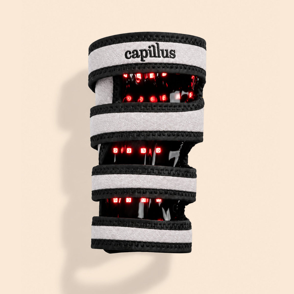 The Capillus Pet Joint Wrap—a wearable device with gray and black bands—emits red LED lights, utilizing near-infrared light therapy designed for joint health in pets, displayed on a beige background.