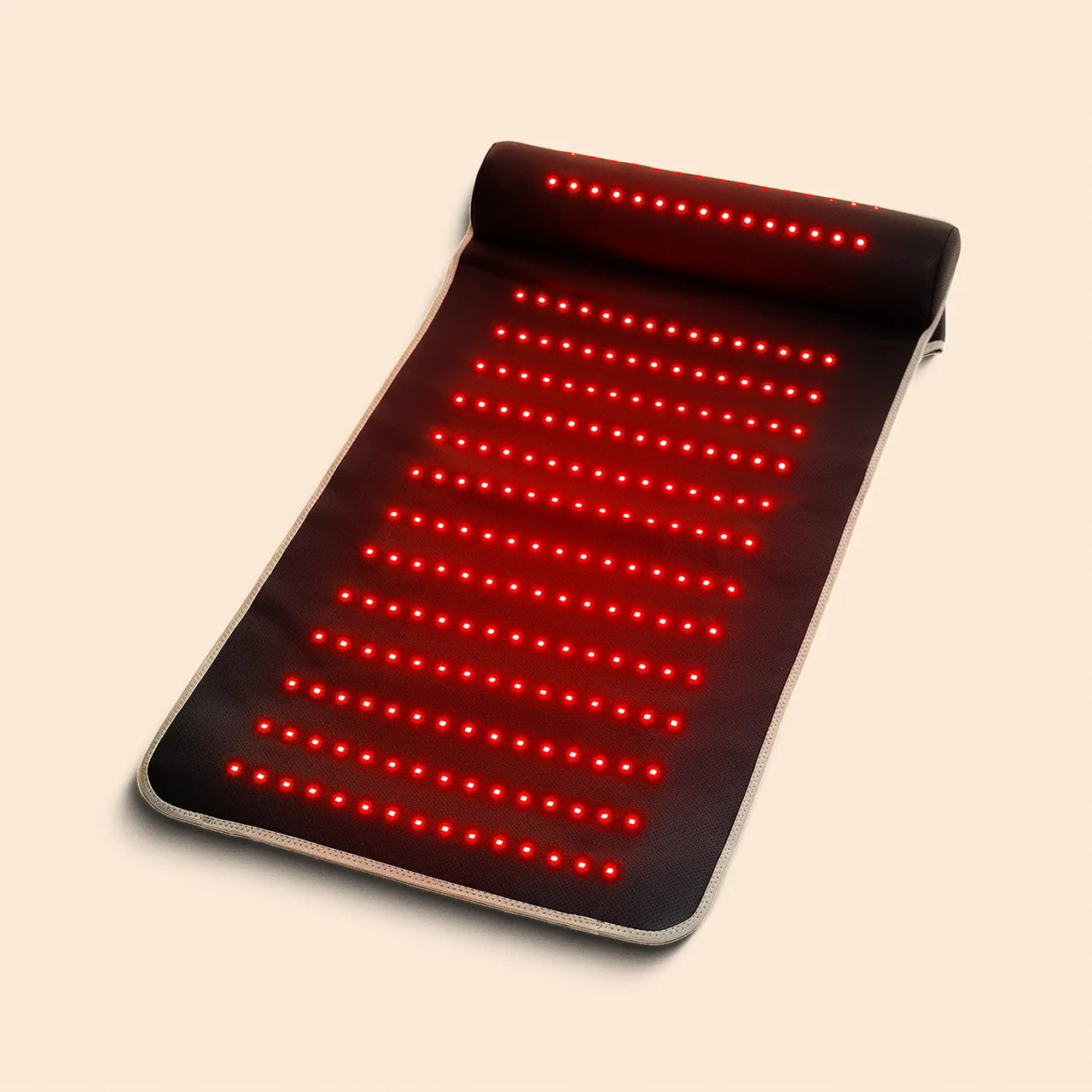 The Capillus Red Light Therapy Mat by Capillus, shown partially rolled up on a light background, features rows of bright 660nm red LED lights in a sleek black design.