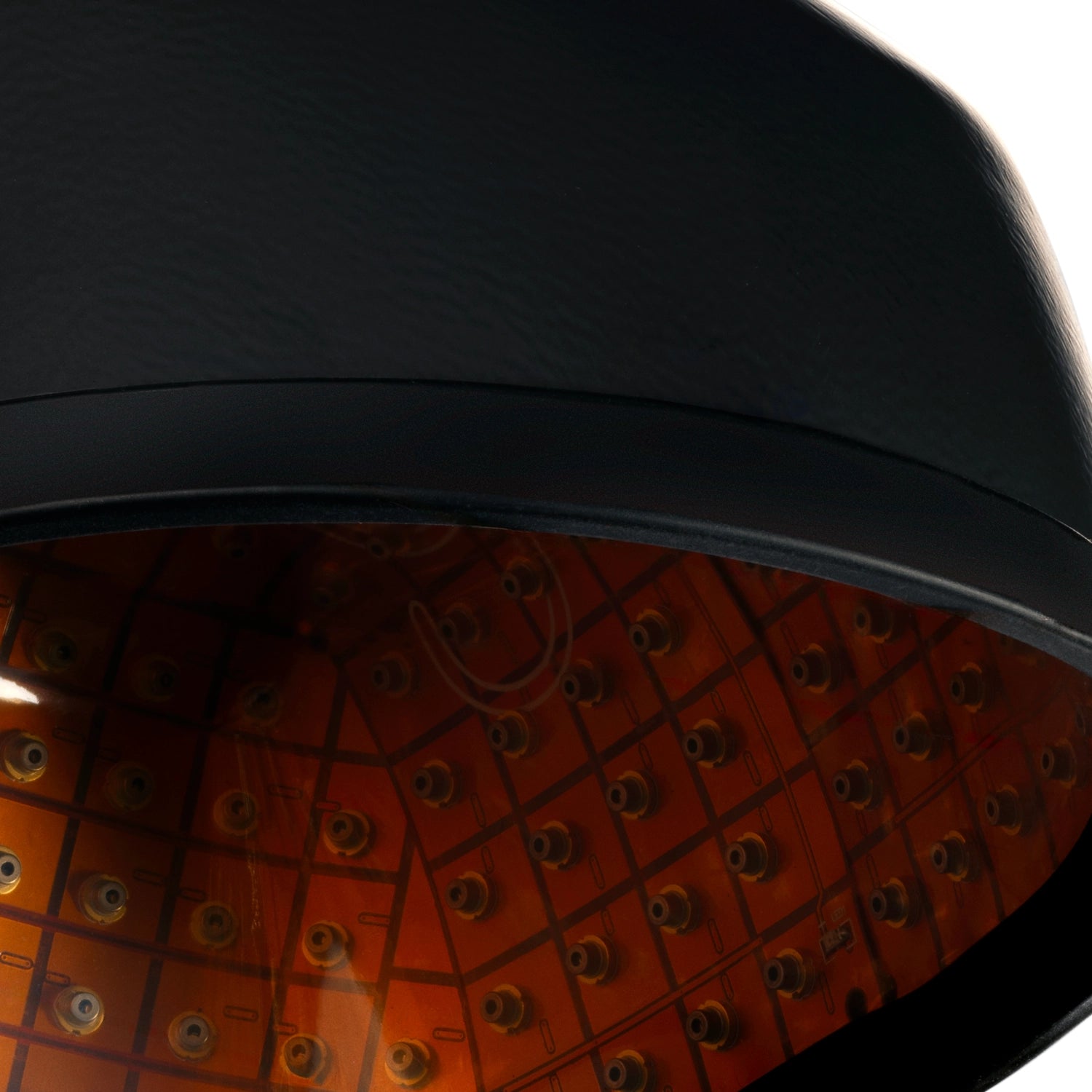 Close-up of the inside of a black and orange device with multiple small LED lights arranged in rows, likely a hair or scalp treatment cap.